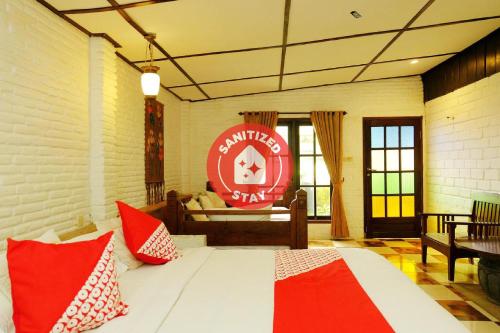 巴图OYO 604 Cemara's Homestay的一间卧室配有一张带红色和白色枕头的大床