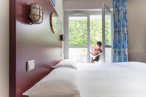 拉罗谢尔拉罗谢尔珀品斯海上人家酒店的站在卧室里,眺望窗外的人