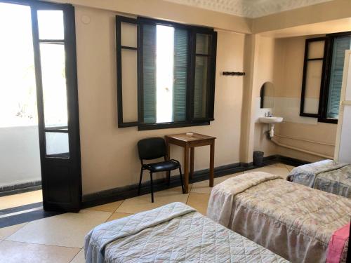 纳祖尔Hotel El Maghreb Al Kabir的客房设有两张床、椅子和桌子。