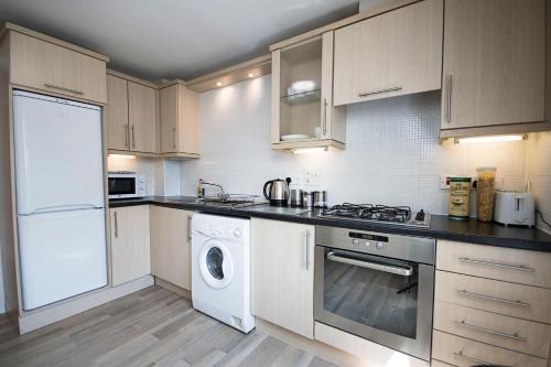 爱丁堡洛琛德服务公寓的厨房配有白色橱柜、洗衣机和烘干机
