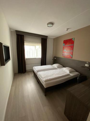 哈尔夫韦赫阿姆斯特丹-史基浦-哈伏威格凯泽斯库瑞姆酒店的一间大卧室,配有两张床和电视