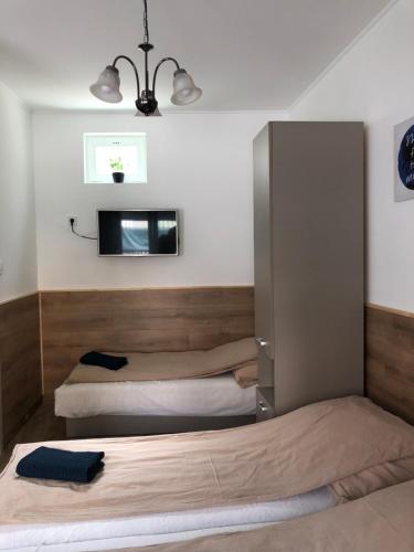 米什科尔茨Avas Apartman的一间卧室设有两张床,墙上配有电视。
