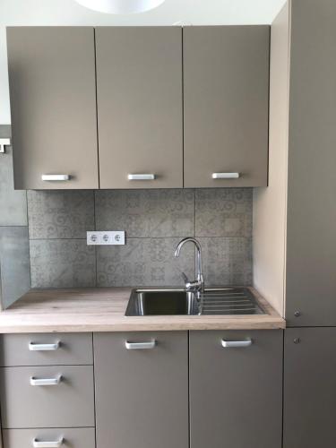 米什科尔茨Avas Apartman的厨房配有白色橱柜和水槽