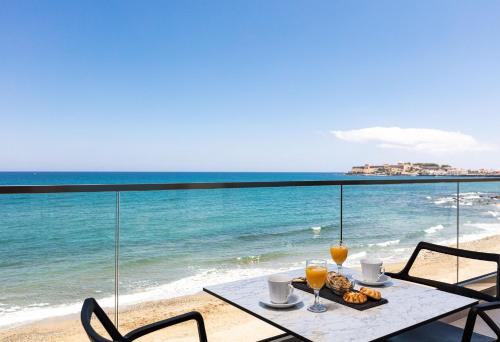 罗希姆诺North Coast Seaside Suites的海滩上的一张桌子,上面放着饮料和一盘食物