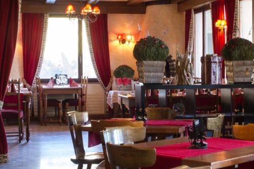 安塞热迷人的珀斯特酒店的一间配备有桌椅和红色窗帘的用餐室