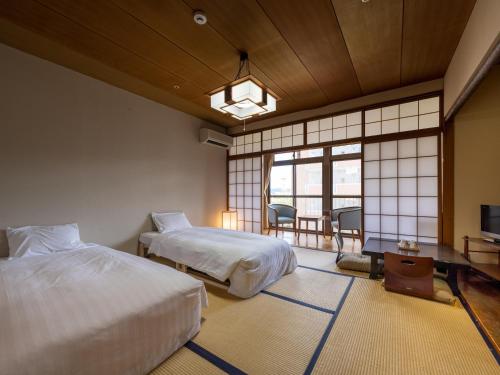 谏早市Hotel Flags Isahaya Nagasaki的酒店客房设有两张床和电视。