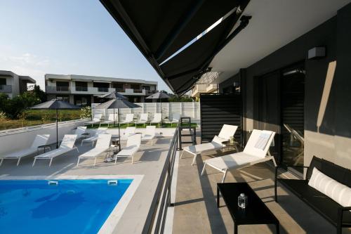 耶拉基尼ISALOS GERAKiNi的一个带白色椅子的庭院和一个游泳池