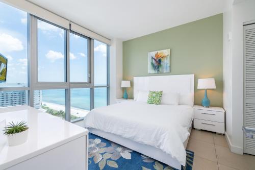 迈阿密海滩蒙特卡洛全球奢华套房公寓式酒店的卧室设有白色的床和大窗户