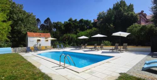 库里亚Hotel Do Parque, Boutique Hotel - Curia的庭院内带椅子和遮阳伞的游泳池