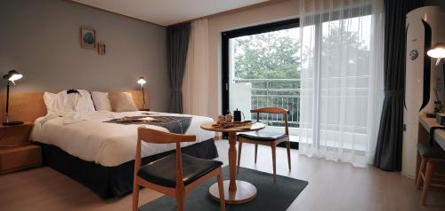 襄阳郡The N Resort Hotel&Spa YangYang的一间卧室配有一张床、一张桌子和一个窗户。