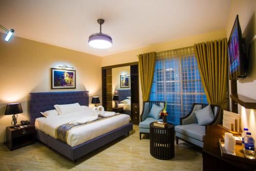 达卡Shinepukur Suites的一间卧室配有一张床、一台电视和一张沙发