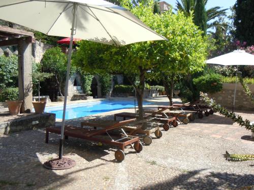 特鲁希略查韦斯宫酒店的一组躺椅和一把遮阳伞,位于游泳池旁