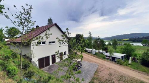 GütenlandCamping Haus Seeblick的山坡上的白色房子,有土路