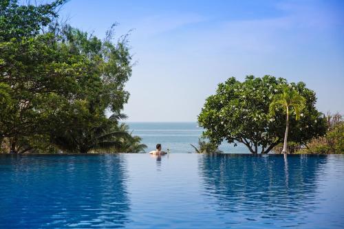美奈维多利亚潘切海滩Spa度假酒店的背景海洋的无边游泳池里的人