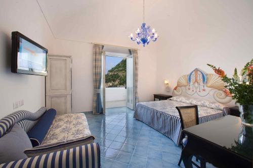 波西塔诺Palazzo Marzoli charme Resort - Small Luxury Hotel的一间卧室配有一张床、一张沙发和一张桌子