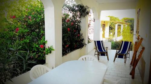 兰佩杜萨Appartamento con giardino的门廊上摆放着白色的桌椅,鲜花盛开