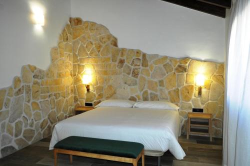 布里韦加Hostal Restaurante Villa de Brihuega的卧室配有白色的床和石墙
