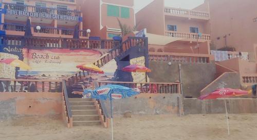 西迪伊夫尼HOTEL BEACH CLUB LEGZIRA的海滩上带楼梯和遮阳伞的游乐场