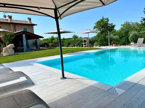 巴多利诺Poggio Bardolino的一座房子旁带遮阳伞的游泳池