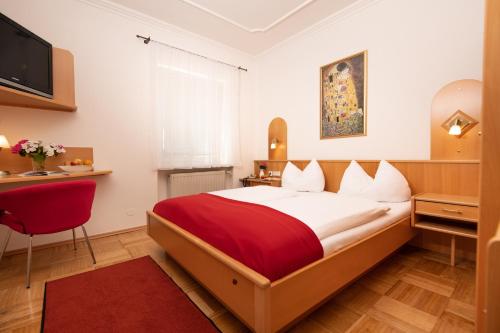 克拉根福Hotel Liebetegger-Klagenfurt的一间卧室配有一张带红色毯子的大床