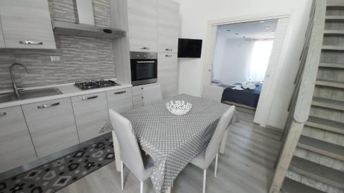 兰佩杜萨Case Vacanze Porto Vecchio的厨房配有带白色椅子的桌子和水槽