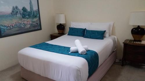 黄金海岸贝卡昂勒酒店的卧室配有带蓝色枕头的大型白色床