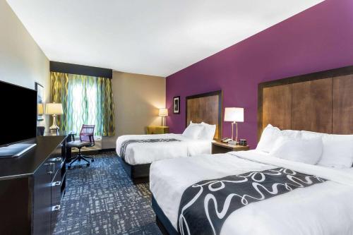 莫纳汉斯La Quinta by Wyndham Monahans的酒店客房设有两张床和紫色墙壁。