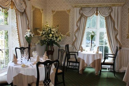 兰鲁斯特梅南修道院酒店的用餐室配有2张桌子和椅子,鲜花盛开