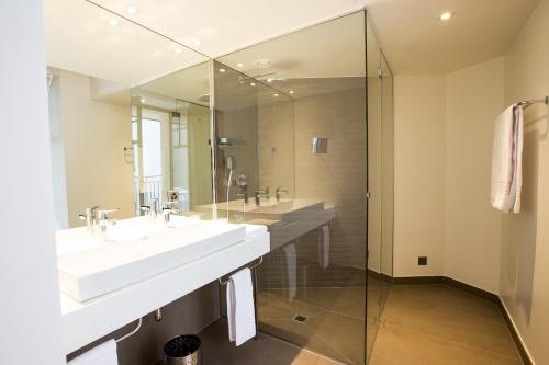 洛桑旅客精品酒店的一间带两个水槽和玻璃淋浴间的浴室