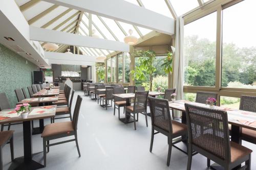 伊普尔Flanders Lodge Hotel的用餐室设有桌椅和窗户。