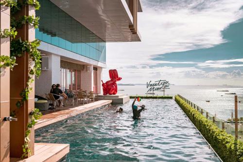 芭堤雅市中心Mytt Hotel Pattaya - SHA Extra Plus的度假村的游泳池,两人玩飞盘