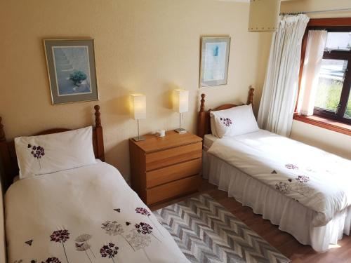 皮特洛赫里Newholme Self-Catering Bungalow的一间卧室设有两张床和窗户。