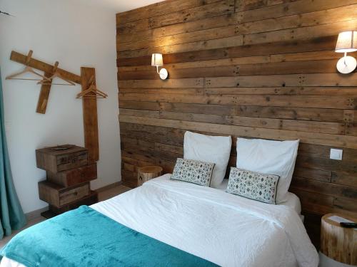 ChampdolentChambres d'hôtes Les Marguerites的一间卧室设有木墙和一张带两个枕头的床