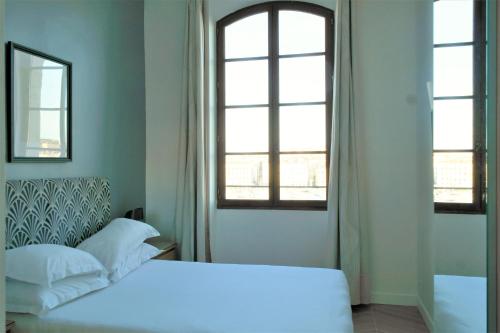马赛Hotel Belle-Vue Vieux-Port的卧室配有白色的床和2扇窗户。