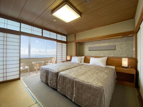 NishioMikawa Bay Hills Hotel的一间卧室设有一张大床和一个大窗户