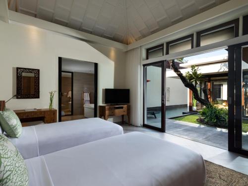 塞米亚克Avani Seminyak Bali Resort的一间卧室设有两张床、一台电视和一扇窗户。