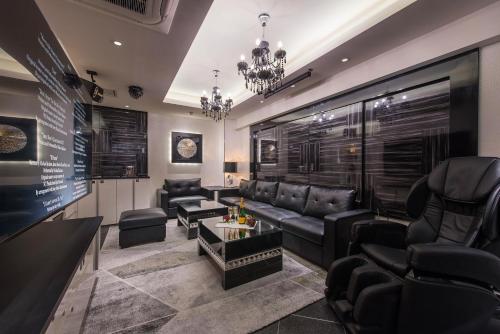 滨松HOTEL Dior7的客厅配有黑色皮革家具和吊灯。
