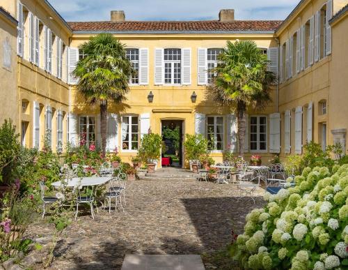 圣马丹德雷La Baronnie Hôtel & Spa - Teritoria的建筑前方的庭院配有桌椅