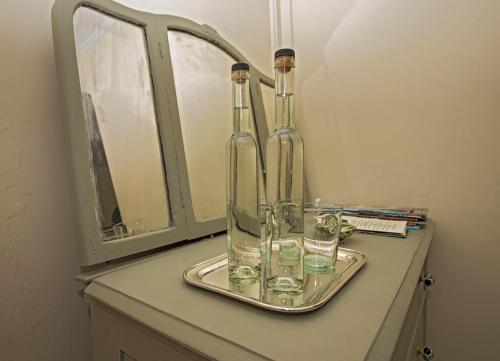PalenvilleThe Woodbine Inn的两瓶和玻璃杯坐在镜子旁的托盘上