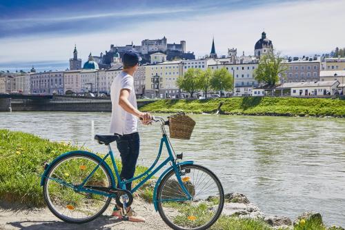 萨尔茨堡优博夫尔精品酒店的站在自行车旁的河前的人