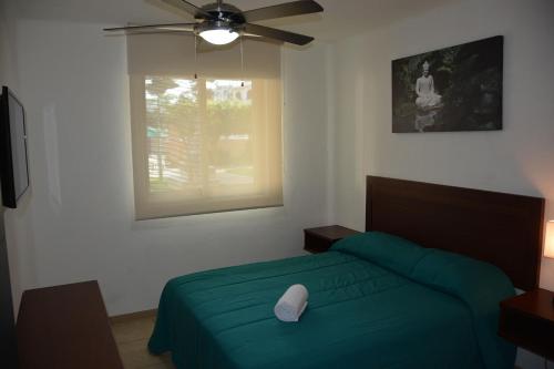 巴亚尔塔港Zenharmony Suites的一间卧室配有绿色的床和吊扇