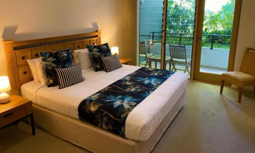 棕榈湾棕榈湾保护区酒店的一间带大床的卧室和一个阳台