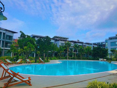 富国Anise hotel的一座带椅子和建筑的大型蓝色游泳池