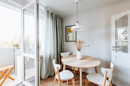 格丁尼亚Gdynia Square Apartment的一间小餐厅,配有木桌和白色椅子