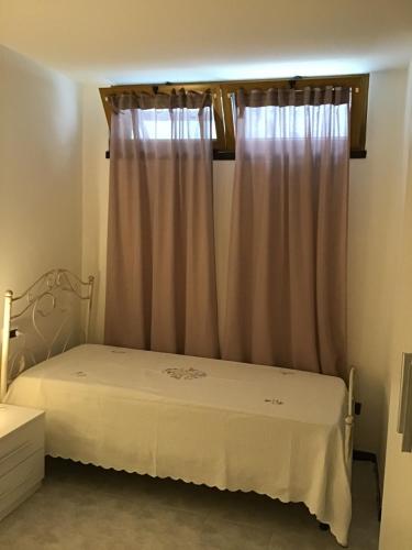 MiggianoCasa-Lisa seminterrato的卧室配有白色的床和窗户。