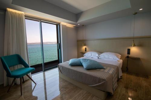 AiándionAianteion Bay Luxury Hotel & Suites的一间卧室配有一张床、一把椅子和一个大窗户