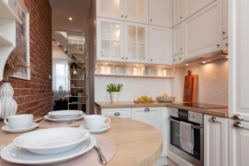 什切青Apartamenty Profesorskie的厨房配有白色橱柜和木桌