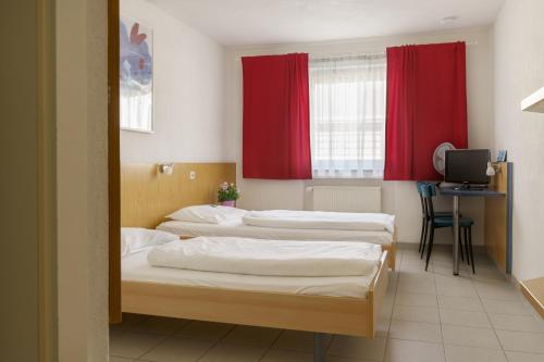HeimsheimMotel Drei König- Ihr Transithotel的带红色窗帘的客房内的三张床