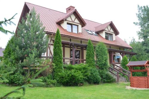 FredropolAgroturystyka Leśny Potok的一座带瓷砖屋顶和一些树木的房子