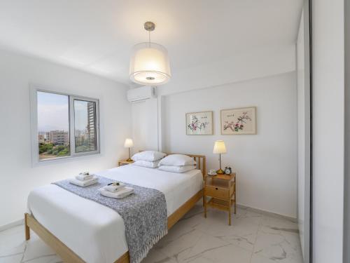 拉纳卡Mackenzie Leo Seafront Suite的白色卧室配有两张床和一张桌子